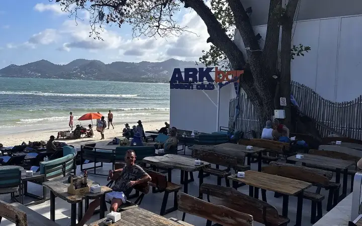 טרסה עם שולחנות עץ על החוף ב-Ark Bar